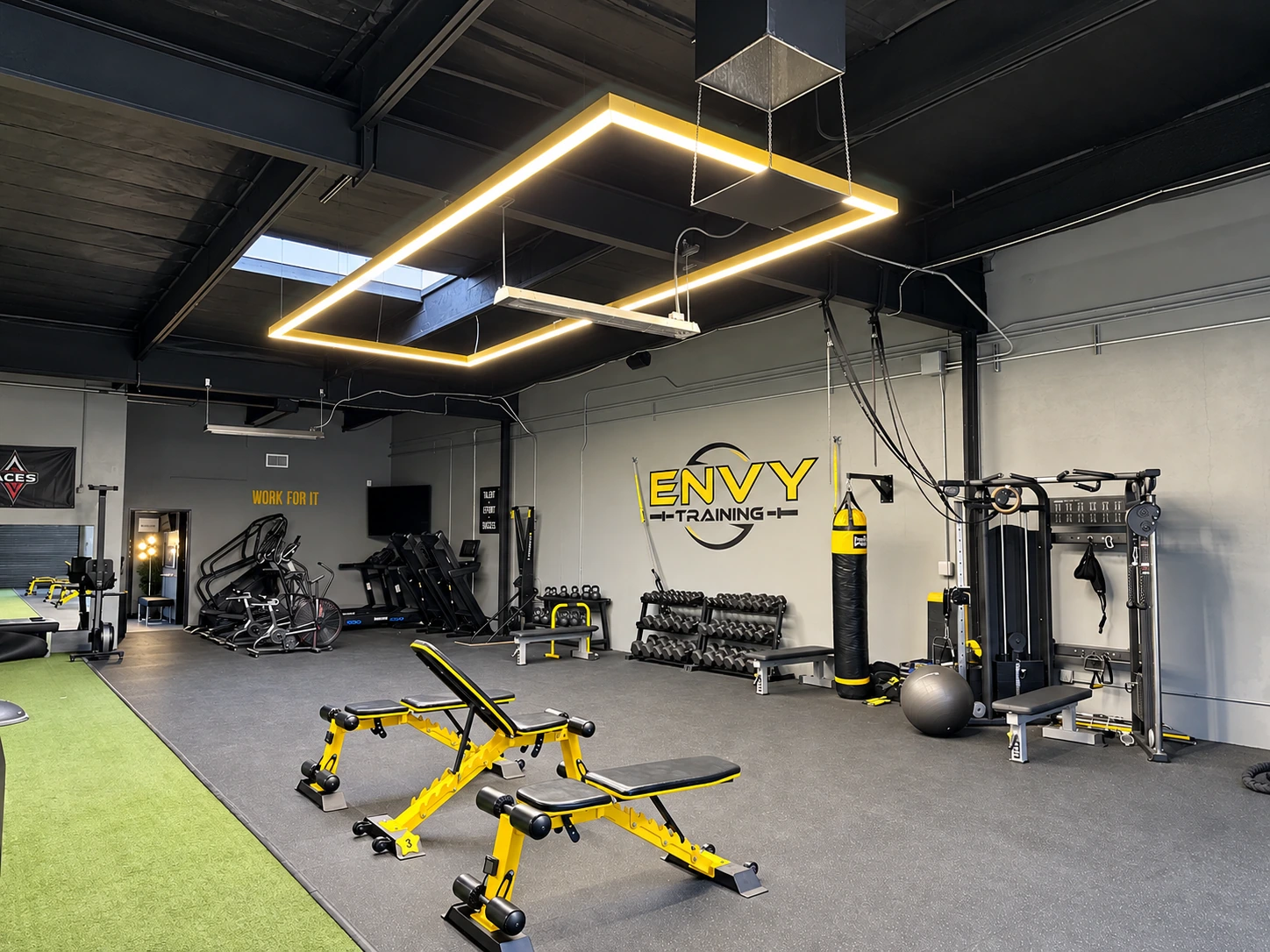 Fitness studio with a suspended rectangular light fixture and exercise equipment