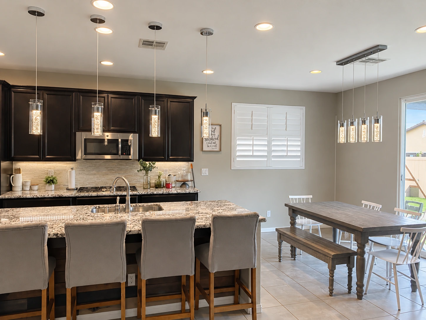 Residential kitchen and dining space with pendants and recessed lighting
